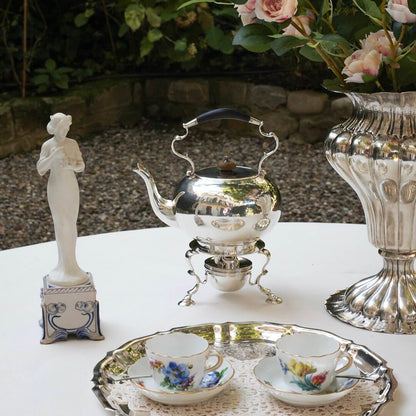 Victorian Sterling Silver Tea Kettle. outdoors with silver vase, coffee cups, and antique figurine 